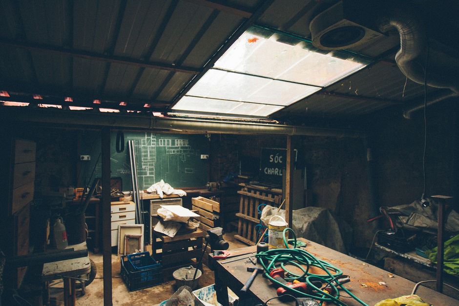 Cluttered basement workshop space full of tools and stored items before clearance