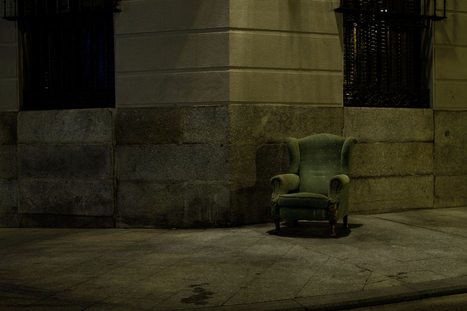 A worn armchair left outside against a wall, ready for bulky waste collection