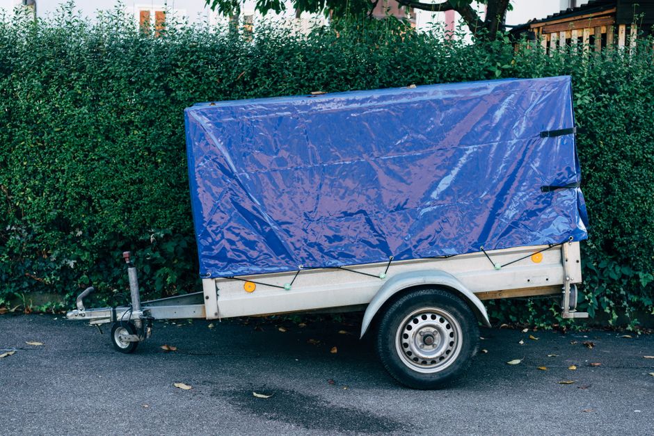 A small covered box trailer parked at the roadside, the kind of trailer a vehicle permit would need to cover