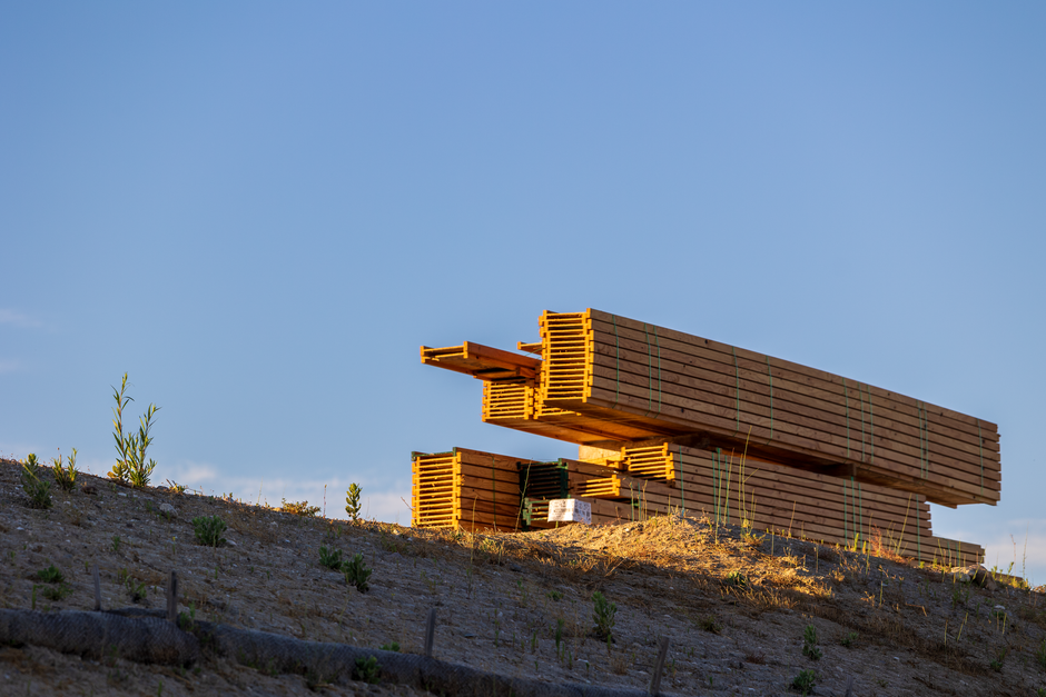 Stacked timber lengths at a building site, set aside from general waste