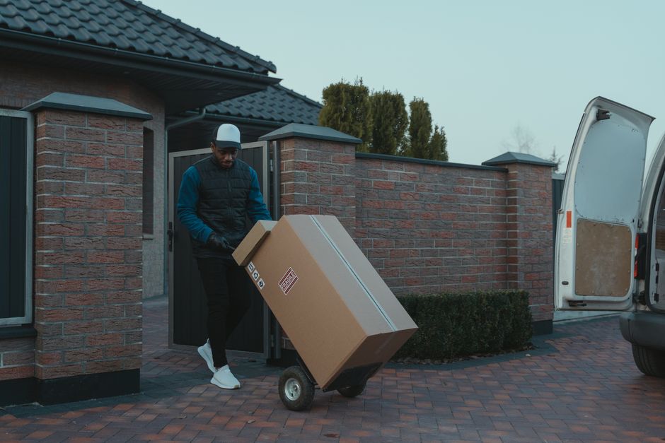 Cardboard moving boxes being wheeled on a sack truck beside a removal van