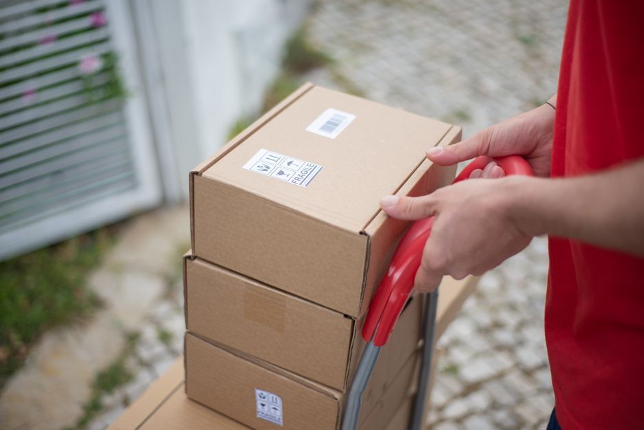 Stack of cardboard parcels with fragile labels on a trolley ready for collection