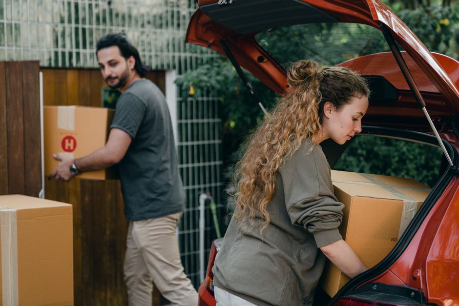 A couple loading cardboard boxes into the boot of a car ahead of a trip to the recycling centre