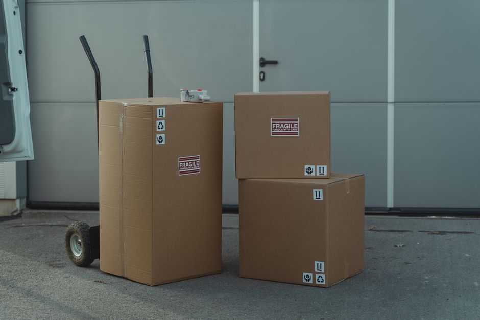 Cardboard parcels with fragile stickers stacked on a hand truck ready for collection