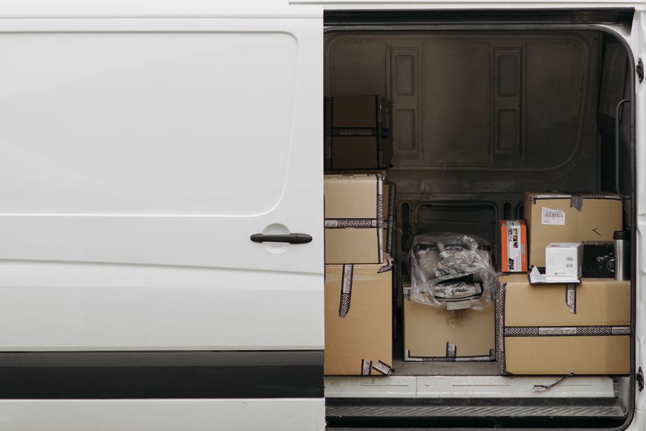 The open rear doors of a delivery van loaded with cardboard parcels