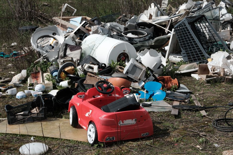 Mixed old appliances and household junk dumped outdoors on waste ground