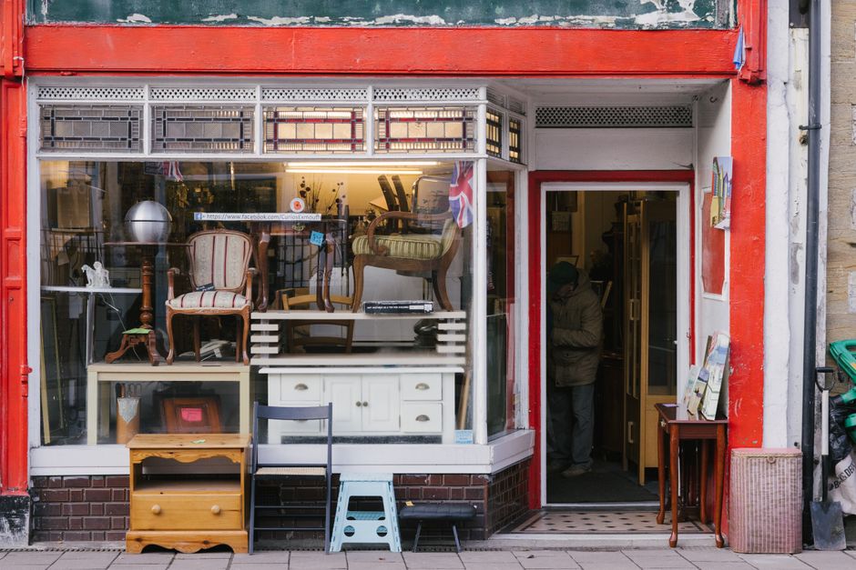 A secondhand furniture shop front in the UK with chairs and cabinets on display