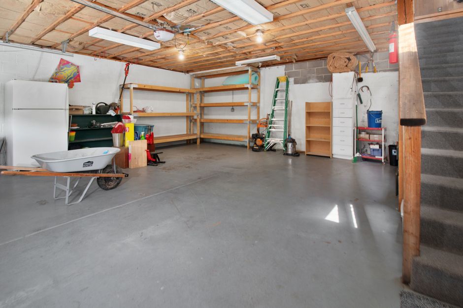 A home garage with wooden shelving, a wheelbarrow and stored tools and boxes