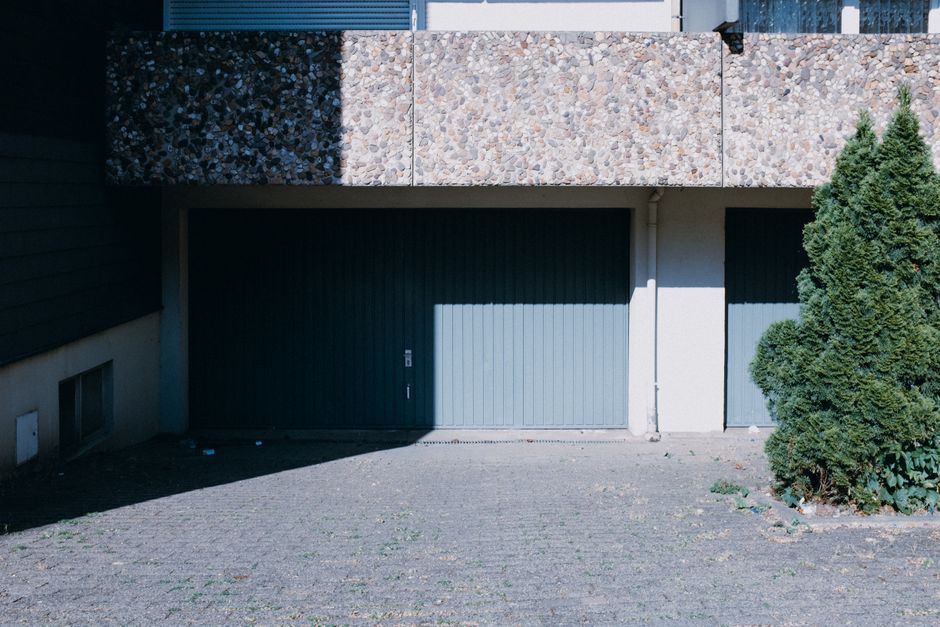 A dark up-and-over garage door set into a house frontage with a short driveway
