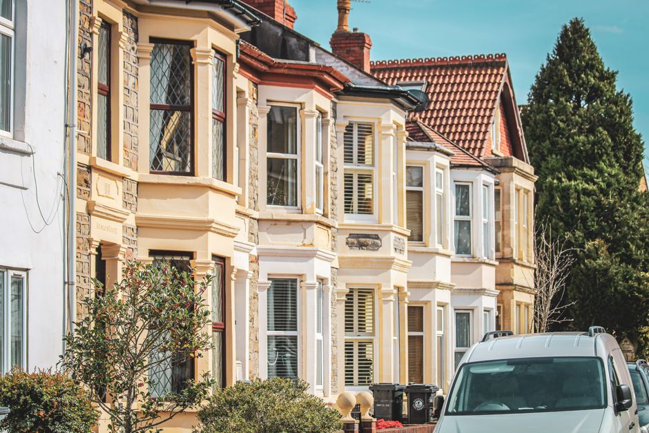 A row of Victorian bay-window terraced rental houses with wheelie bins by the doors and a van parked outside