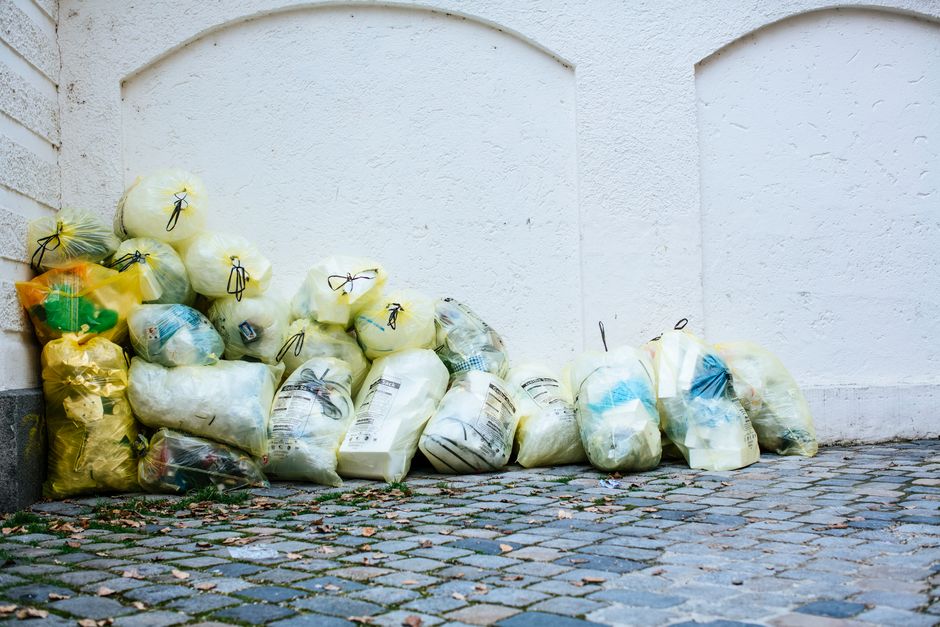 Pile of tied rubbish bags stacked against a wall awaiting household waste collection