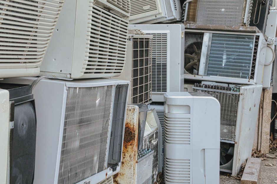 Stacked discarded air-conditioning units and old appliances awaiting scrap metal collection and recycling